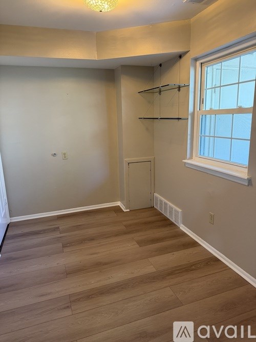 A room with a window and a wooden floor.