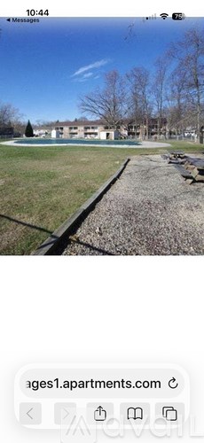A park with a building in the background and a bench on the right side.