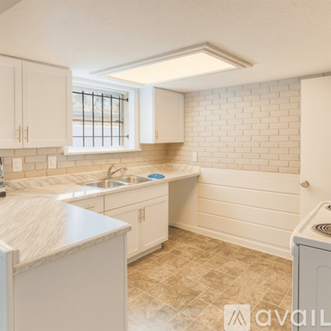 A kitchen with white cabinets and a marble countertop.
