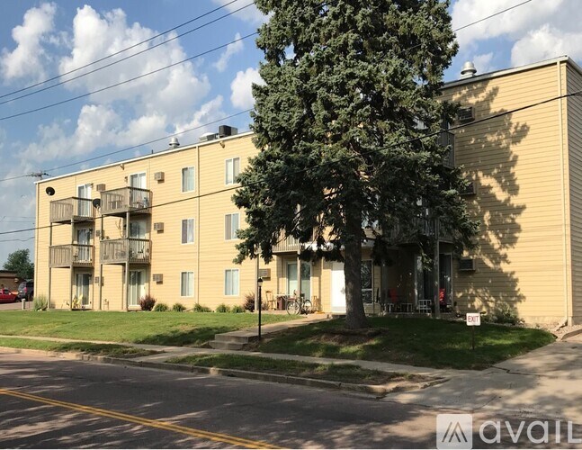A large apartment building with a tree in front of it.