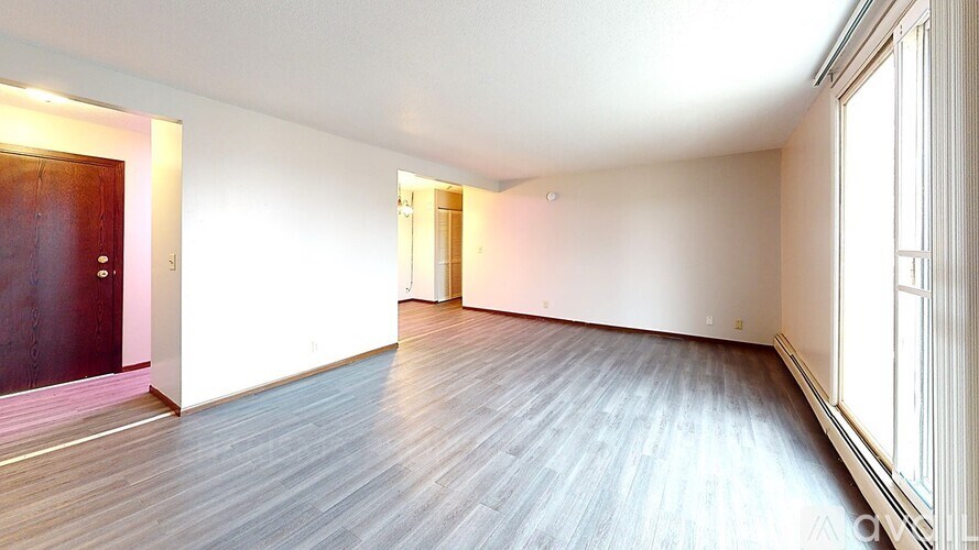 A room with a wooden floor and a window on the right side.