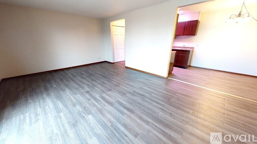 A room with wooden flooring and a doorway leading to another room.