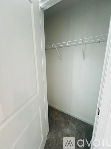 A white closet with a hanger bar and a door.