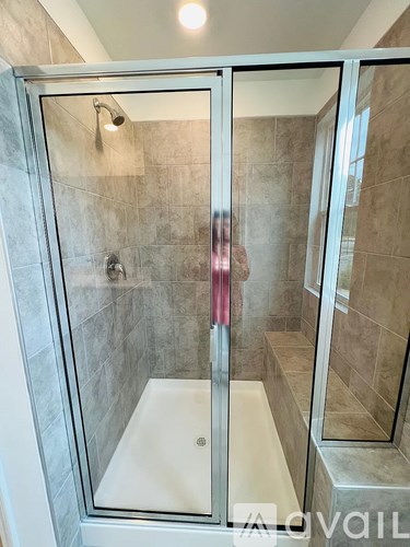 A glass shower stall with a white tub and a glass door.