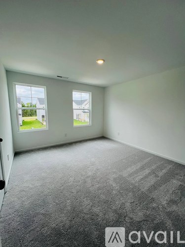 A carpeted room with two windows and a door.