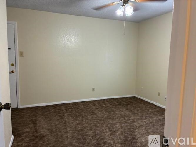 A room with a ceiling fan and carpeted floor.