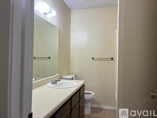 A bathroom with a toilet, sink, and mirror.