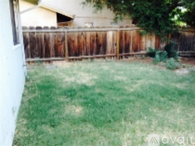 A backyard with a wooden fence and a house in the background.
