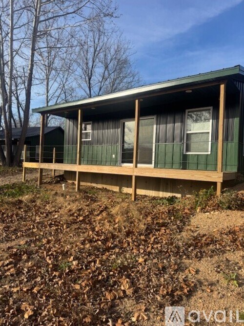A green house with a brown roof and a brown fence.