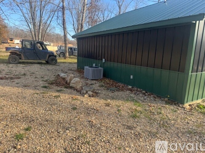 A green building with a metal roof and a truck in the background.