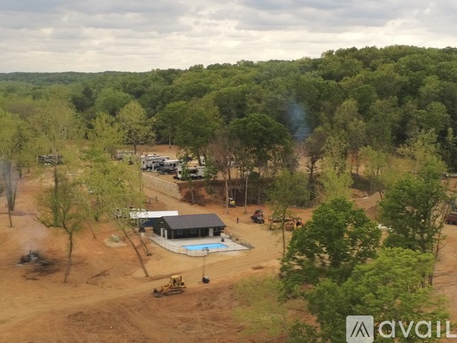 A house with a pool is surrounded by trees and construction equipment.