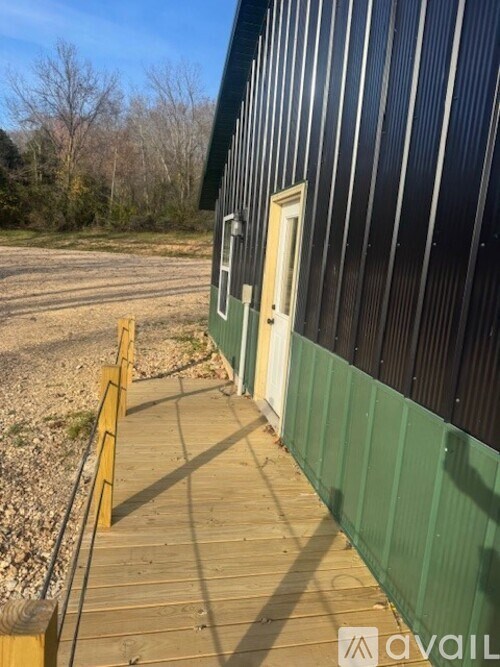 A green building with a white door and a wooden walkway leading to it.