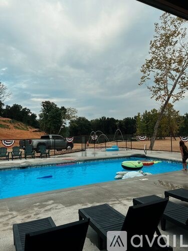 A pool with a person standing on the edge and a truck parked in the background.