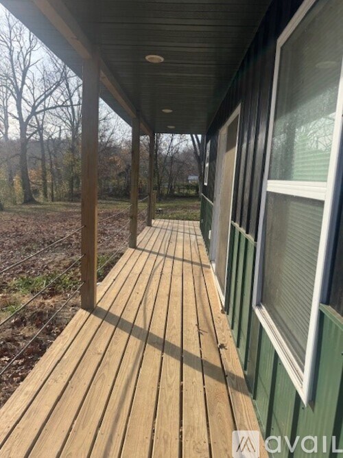 A wooden deck with a green wall and a window.