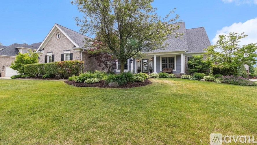 A house with a well-manicured lawn and a tree in front.