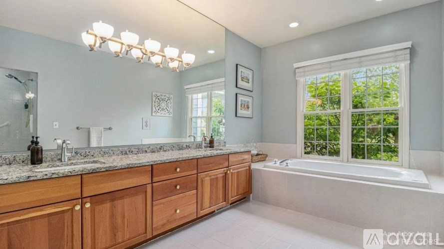 A well-lit bathroom with a large tub and a window.