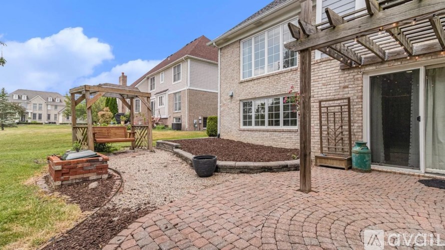 A backyard with a brick patio and a wooden pergola.