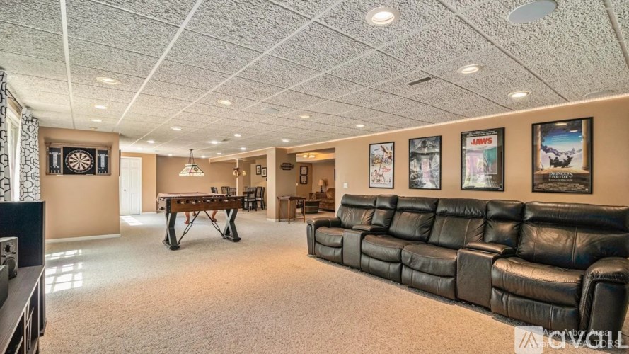 A living room with a black leather couch and a pool table.