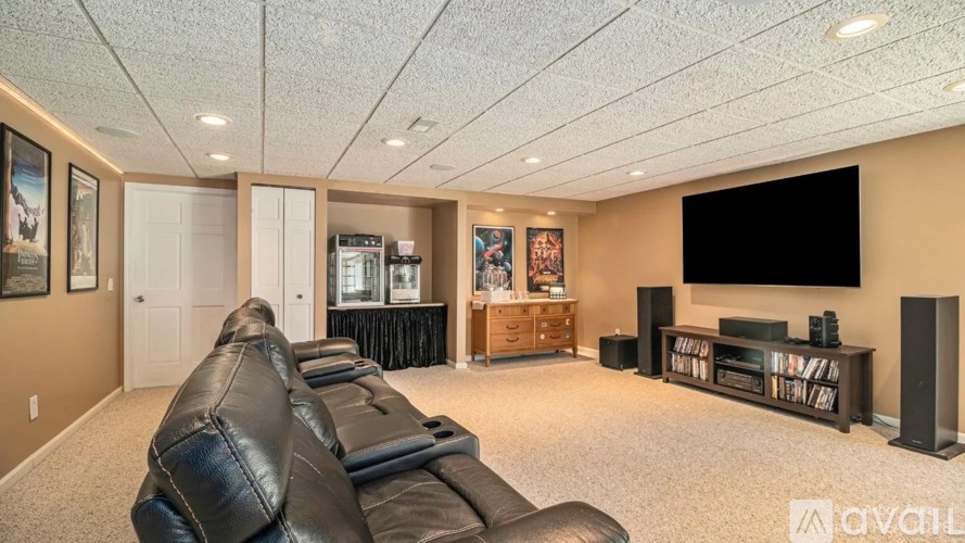 A living room with a black leather couch and a flat screen TV.