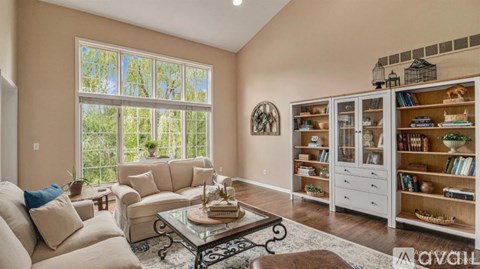 A living room with a glass table and a large window.
