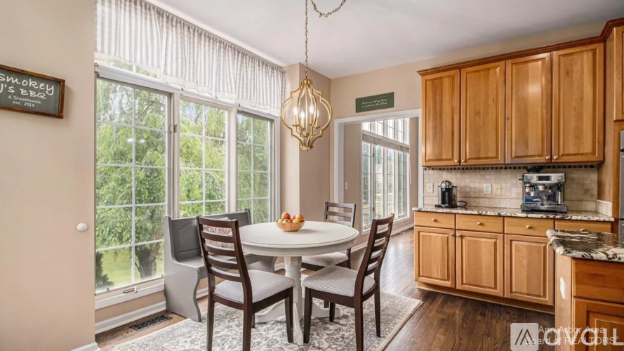 A dining room with a table set for two and a chandelier hanging from the ceiling.