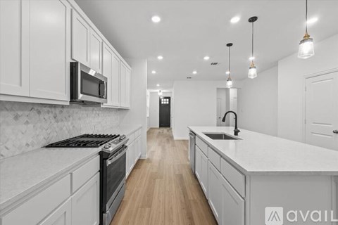 A modern kitchen with white cabinets and a wooden floor.
