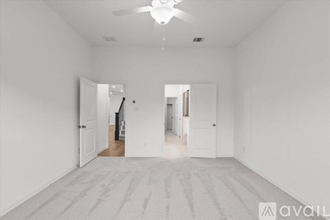 A spacious, empty room with a carpeted floor and a ceiling fan.