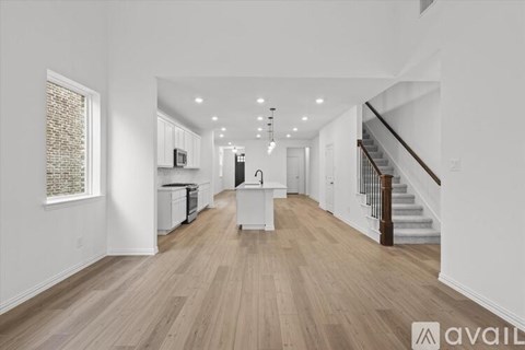 A spacious living room with wooden floors and a staircase on the right side.