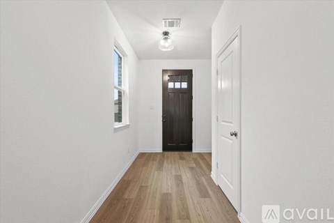 A hallway with a wooden floor and a white door.