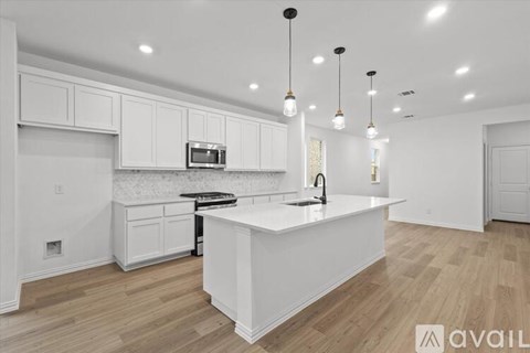 A modern kitchen with white cabinets and a wooden floor.