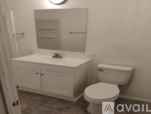 A white bathroom with a toilet, sink, and cabinet.