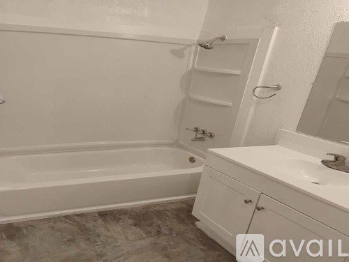 A white bathroom with a tub, sink, and mirror.