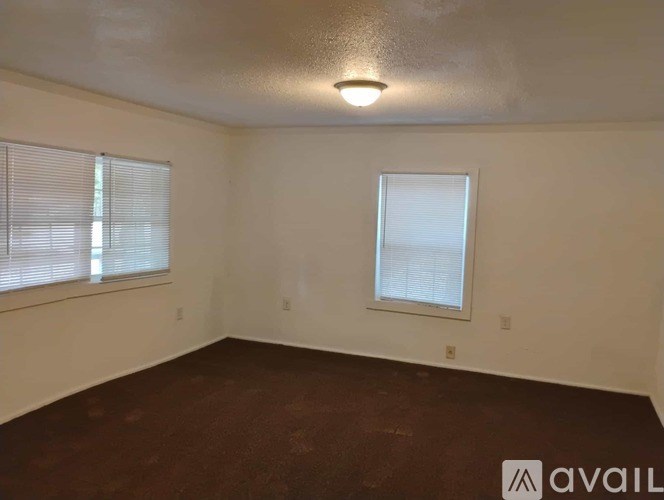 A room with a window and a brown floor.