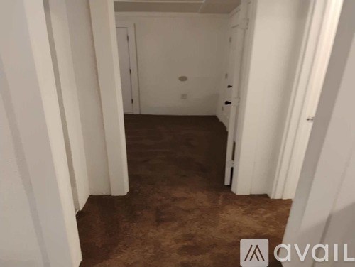 A hallway with brown carpeting and white walls.