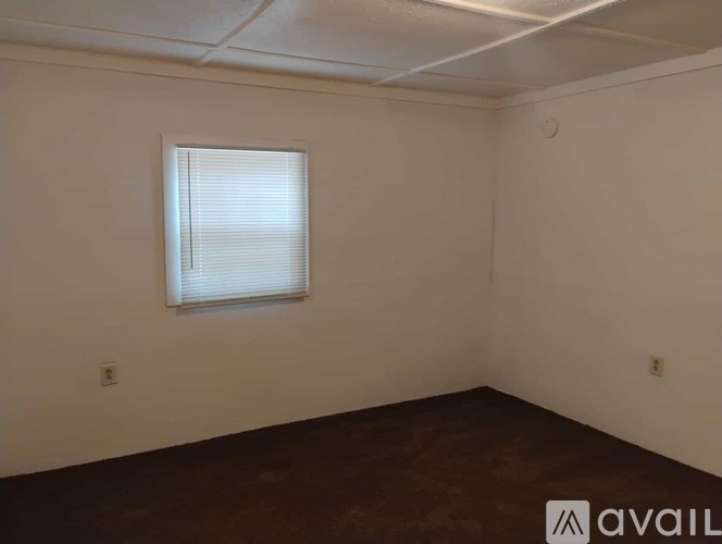 A room with a window and a brown floor.