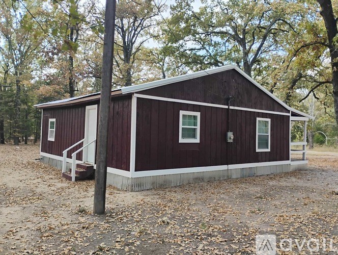A small red building with a white trim is surrounded by fallen leaves.
