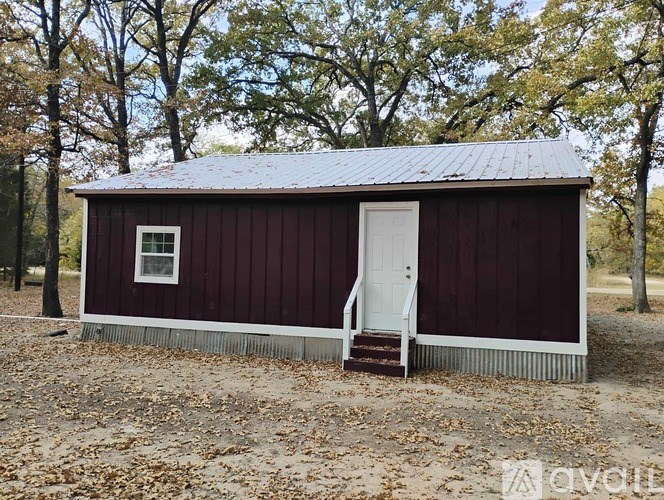 A small red barn with a white door and a small window.