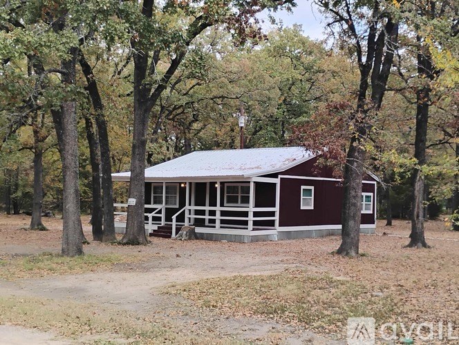 A small red cabin sits in a wooded area.