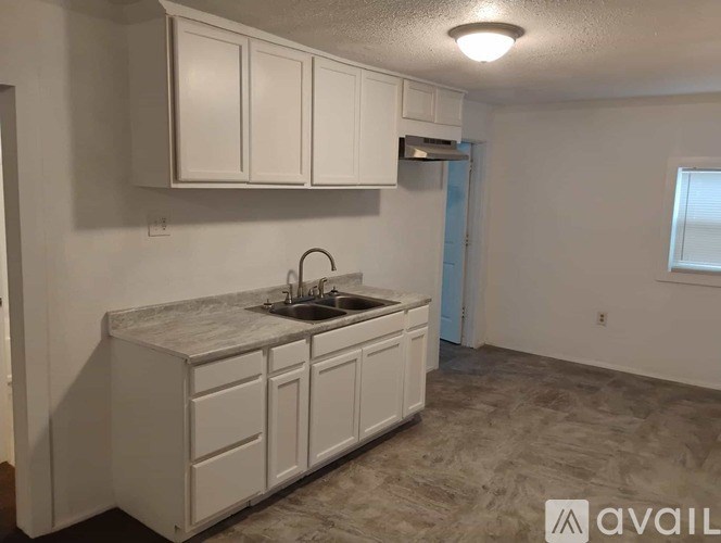 A kitchen with white cabinets and a marble countertop.