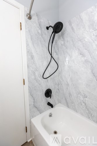 A white bathroom with a marble wall and a white tub.