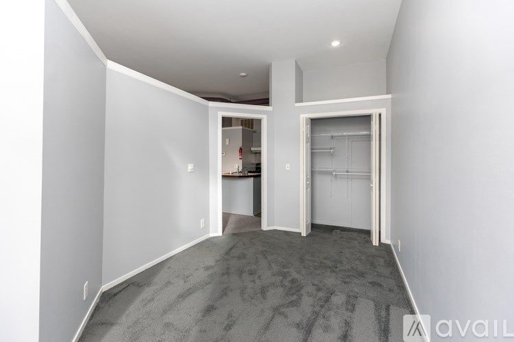 A room with a carpeted floor and white walls, with a doorway leading to another room.