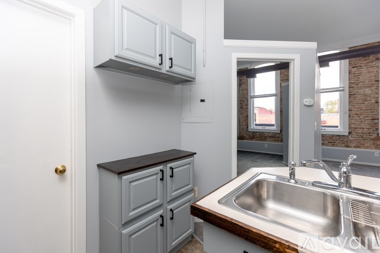 A kitchen with a white door, grey cabinets and a wooden counter top.