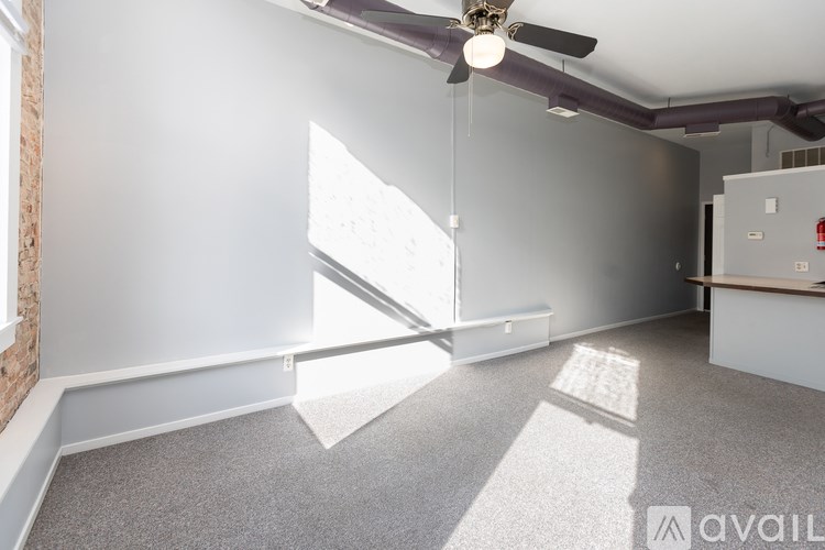 A room with a ceiling fan and a window letting in sunlight.
