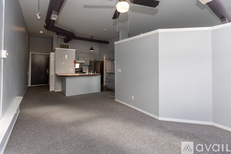 A spacious room with a kitchenette in the background.