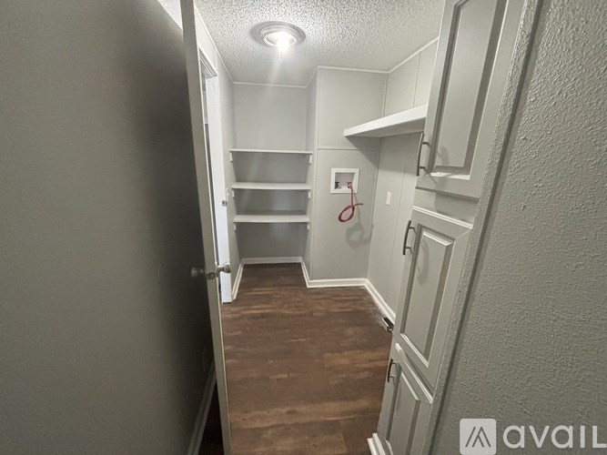 A narrow hallway with a red door and a light on the ceiling.