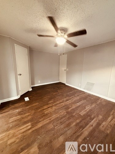 A room with wooden flooring and a ceiling fan.