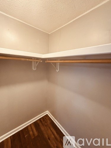 A white wall with a wooden floor and a white shelf.