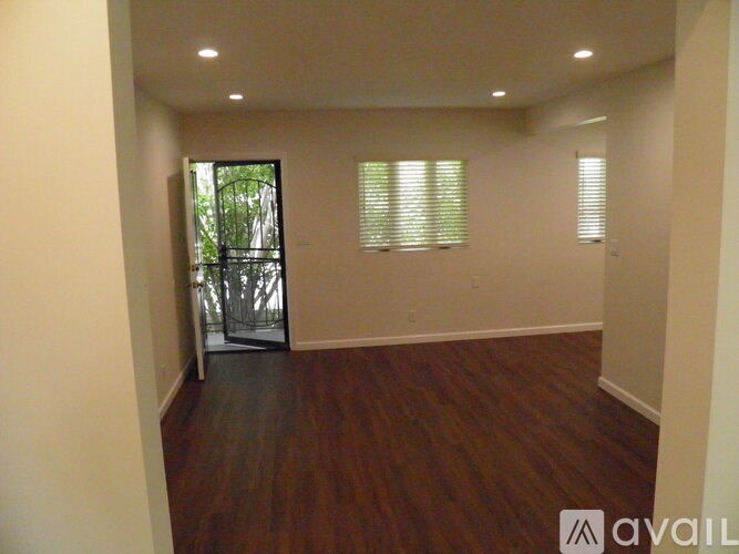 A room with wooden flooring and a sliding glass door leading to a balcony.