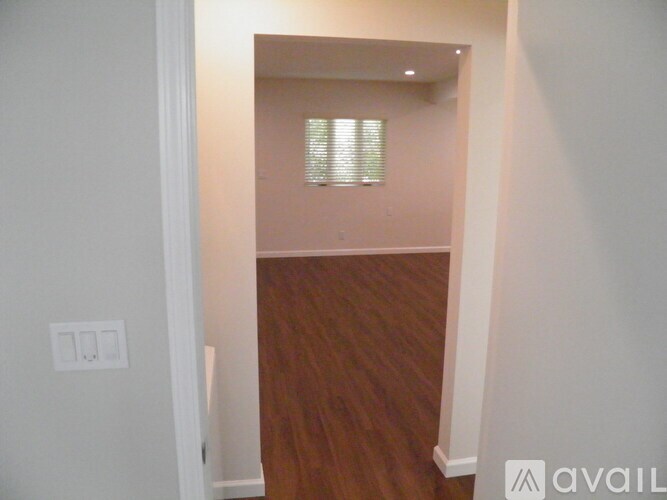 A room with wooden flooring and a window with blinds.