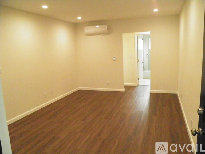 A room with wooden flooring and a door on the right.